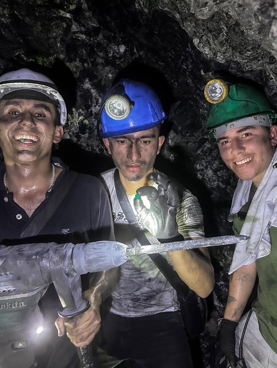 Three artisanal miners underground, smiling, part of Muzo Emerald House's sourcing network